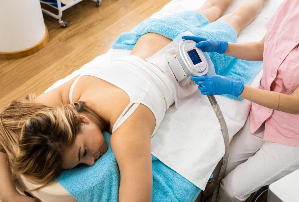 Beautician therapist applying cryolipolysis treatment in beauty salon.